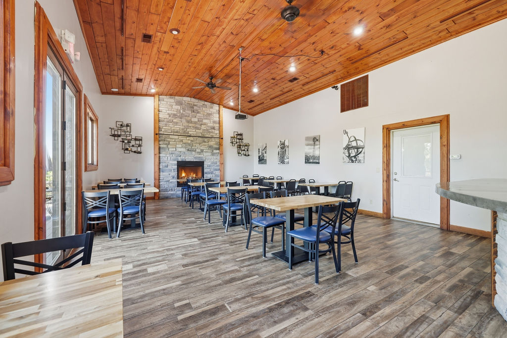 Original photograph: Dining room with cathedral pine ceiling and stone fireplace. Digitally altered: fire added