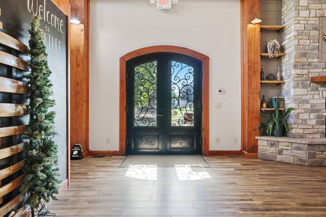 Arched wrought-iron double doors at the main entry; stone chimney mass to the right