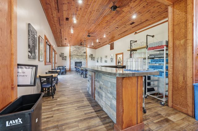 Adjoining dining room with second service bar and stone fireplace at the far end