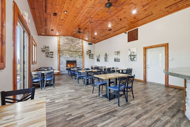 Dining room with cathedral pine ceiling and stone fireplace. Digitally altered: fire added